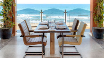 Панорамный вид на ресторан у моря с сервированным столом и видом на пляж Коста-Бланки