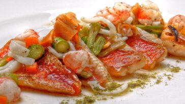 Рыбное блюдо с креветками и овощами в ресторане в Эльче